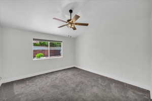Carpeted empty room with a ceiling fan and baseboards