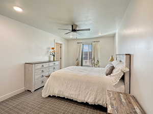 Carpeted bedroom featuring a textured ceiling, a ceiling fan, and baseboards