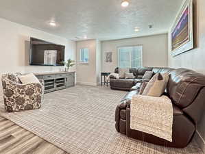 Living area featuring a textured ceiling, baseboards, recessed lighting, and wood finished floors