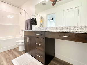 Bathroom with ceiling fan, wood finished floors, vanity, and toilet