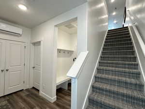 Staircase featuring wood finished floors, an AC wall unit, and baseboards