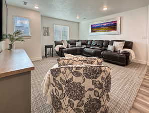 Carpeted living room featuring baseboards, a textured ceiling, and recessed lighting