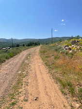 View of dirt / gravel road featuring a view of countryside and a mountain view