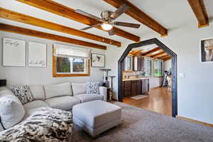 Living room with beamed ceiling, light wood-style floors, and ceiling fan