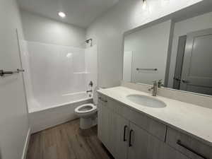 Full bathroom with wood finished floors, vanity, toilet, and shower / bathtub combination