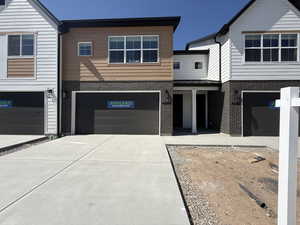 View of front of house featuring driveway, brick siding, a garage, a standing seam roof, and metal roof