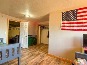 Bedroom with a textured ceiling, wood finished floors, and baseboards