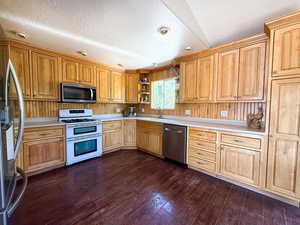 Kitchen featuring stainless steel appliances, light countertops, dark wood finished floors, and a textured ceiling
