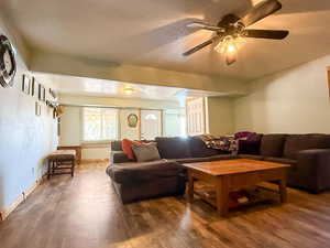 Living area with wood finished floors, a ceiling fan, and baseboards