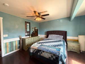 Bedroom featuring wood finished floors, baseboards, a ceiling fan, and a wainscoted wall
