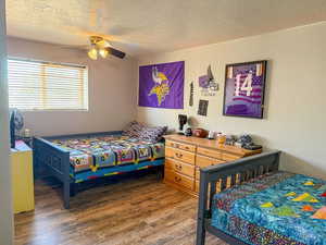 Bedroom with wood finished floors, a textured ceiling, and ceiling fan