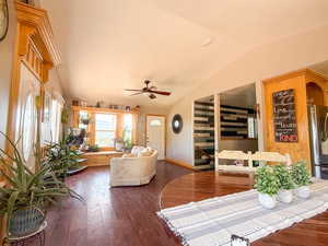 Living room with vaulted ceiling, dark wood-style floors, a ceiling fan, and baseboards