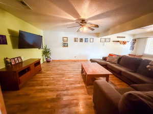 Living area with a ceiling fan, wood finished floors, and a textured ceiling