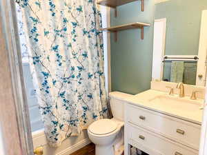 Full bath featuring toilet, vanity, shower / bath combination with curtain, and wood finished floors