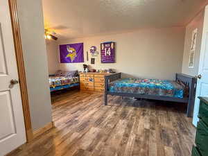 Bedroom featuring wood finished floors, a textured ceiling, and ceiling fan