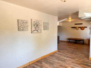 Unfurnished room with a textured ceiling, wood finished floors, and baseboards