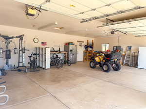 Garage featuring stainless steel fridge, a garage door opener, and freestanding refrigerator