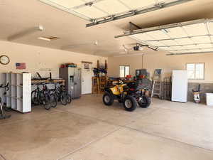 Garage with stainless steel fridge and a garage door opener