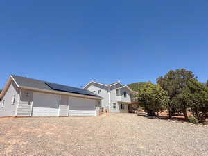 View of front facade featuring solar panels, a garage, and an outbuilding