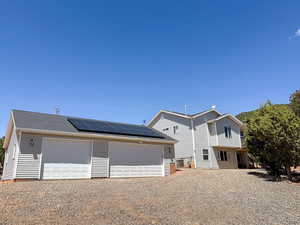 View of front of home featuring a detached garage, roof mounted solar panels, and an outbuilding