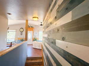 Hallway with lofted ceiling, dark wood-type flooring, and a textured ceiling