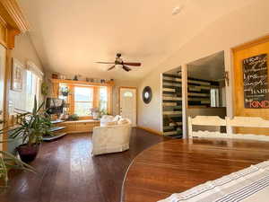 Living room with vaulted ceiling, ceiling fan, dark wood finished floors, and baseboards