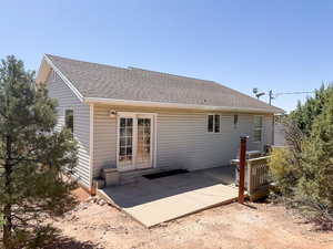 Rear view of house with a shingled roof and a patio