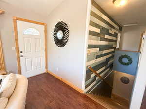 Entrance foyer with dark wood-style flooring, baseboards, and wood walls