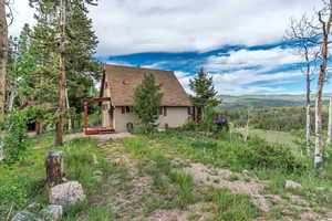 View of side of property with roof with shingles and a deck