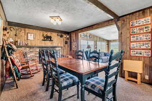 Dining space with carpet floors, wood walls, and a textured ceiling