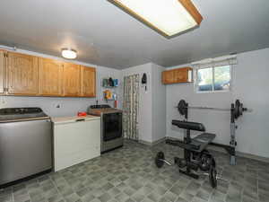 Laundry room featuring washing machine and dryer, cabinet space, and baseboards