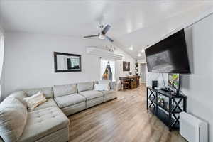 Living area featuring light wood-type flooring, a ceiling fan, and vaulted ceiling