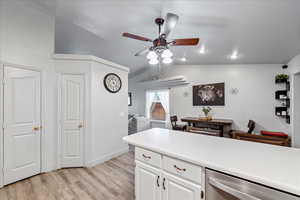 Kitchen featuring dishwasher, light wood-type flooring, a ceiling fan, vaulted ceiling, and white cabinets