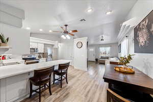 Kitchen featuring appliances with stainless steel finishes, a sink, a ceiling fan, a peninsula, and light countertops