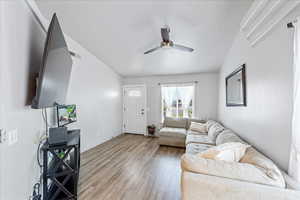 Living area with a ceiling fan, wood finished floors, and baseboards