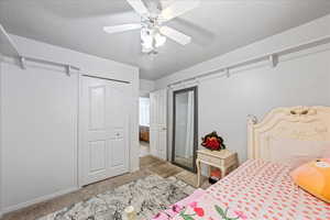 Carpeted bedroom with baseboards, a closet, and ceiling fan