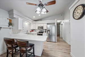 Kitchen with stainless steel appliances, a sink, ceiling fan, a peninsula, and vaulted ceiling