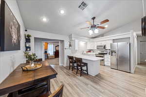 Kitchen featuring appliances with stainless steel finishes, a peninsula, light countertops, a ceiling fan, and vaulted ceiling