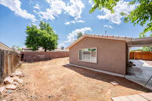 View of side of property featuring a fenced backyard, stucco siding, and a patio
