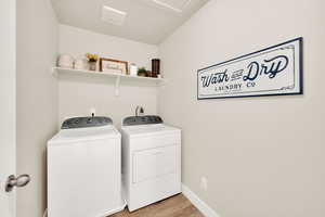 Laundry area featuring washer and dryer, light wood-style floors, and baseboards