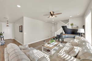 Living room featuring stairs, wood finished floors, a ceiling fan, recessed lighting, and baseboards