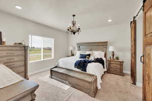 Bedroom featuring a barn door, light colored carpet, baseboards, a chandelier, and recessed lighting