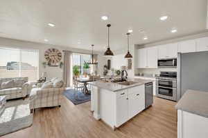 Kitchen with appliances with stainless steel finishes, a sink, light wood-style floors, recessed lighting, and open floor plan
