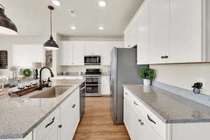 Kitchen featuring appliances with stainless steel finishes, a sink, recessed lighting, white cabinets, and light wood-style floors