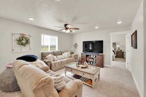 Living area with a ceiling fan, recessed lighting, light colored carpet, a textured ceiling, and baseboards