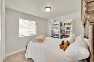 Bedroom with light carpet, baseboards, and a textured ceiling