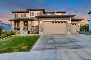 Craftsman-style home with stone siding, an attached garage, concrete driveway, and a front lawn