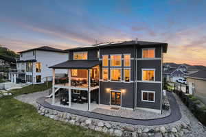 Back of property at dusk featuring a patio and a deck