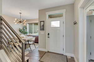 Entrance foyer with wood finished floors, and a chandelier