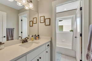 Full bathroom featuring vanity, tile patterned flooring, and a tub to relax in